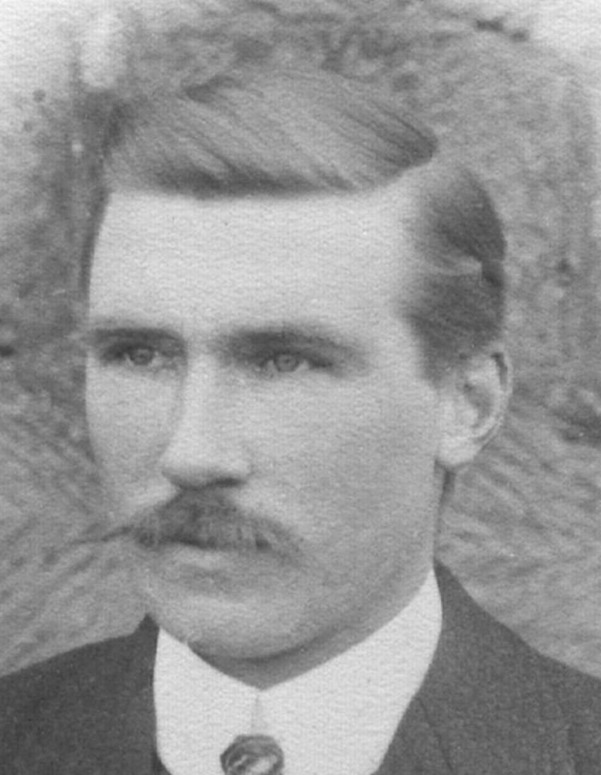 A person with a mustache wearing a suit
Description automatically generated